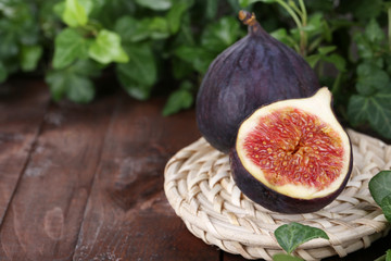 Ripe figs in leaves on wooden table close-up