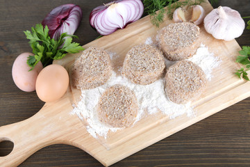 Meat patties on board on wooden table