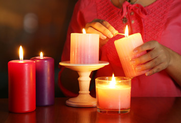 Woman lights candles on bright background
