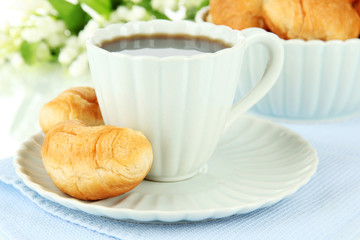 Tasty croissants and cup of coffee on table on white background