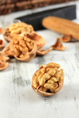Broken walnuts with hammer on wooden table close-up