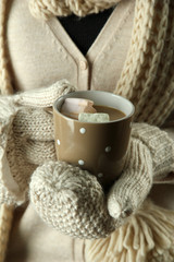 Female hands with hot drink, on color background