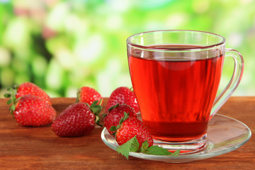 Delicious strawberry tea on table on bright background