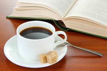 Cup of coffee with sugar and book on wooden background