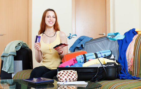  woman sitting on sofa and packing suitcase