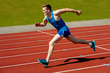 Obraz premium Young caucasian athlete sprinting on track