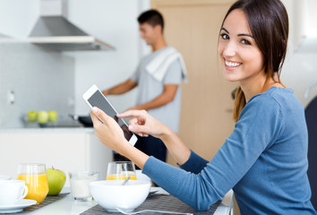 couple in the kitchen preparing breakfast and browsing  internet