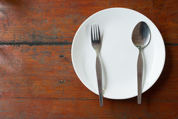 Blank dish, spoon and fork on wood table