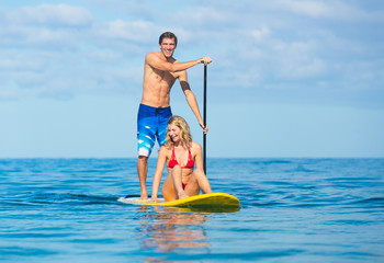 Fototapeta na wymiar Couple Stand Up Paddle Surfing In Hawaii
