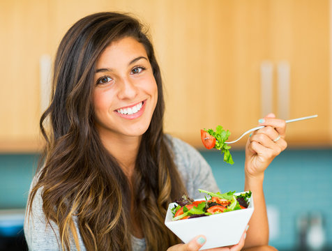 Beautiful young woman eating a bowl of healthy organic salad