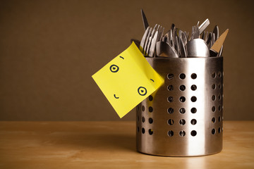 Post-it note with smiley face sticked on a cutlery case