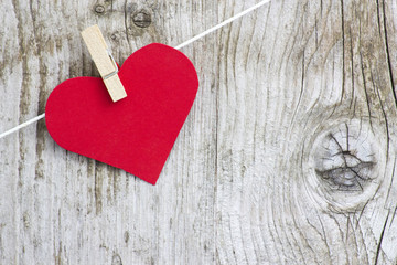 red heart hanging on line against old wood-grain wall
