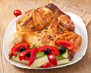 small grilled chicken with vegetables on a white dish