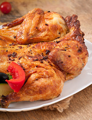 small grilled chicken with vegetables on a white dish