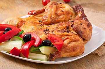 small grilled chicken with vegetables on a white dish