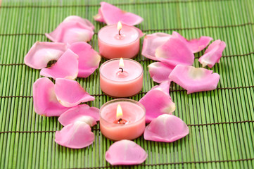 Spa composition of pile of rose petals and row candle