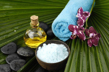 Obraz na płótnie Canvas spa stones ,candle, oil ,salt in bowlon palm leaf texture