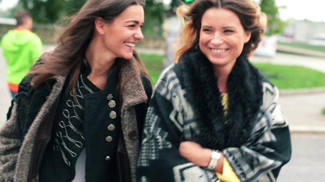 Happy girlfriends walking through street on zebra crossing