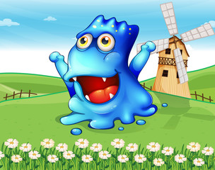 A happy blue monster at the hiltop with a windmill