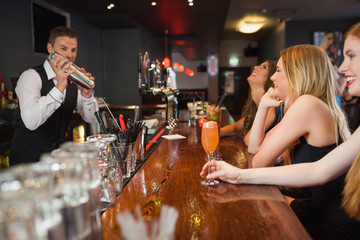 Handsome bartender making cocktails for beautiful women