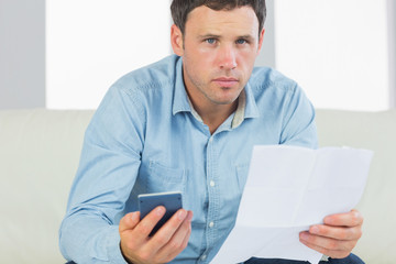 Serious casual man holding calculator and document