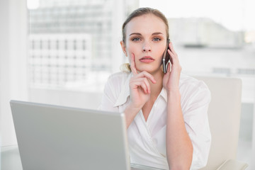 Thoughtful businesswoman using laptop and making a call looking