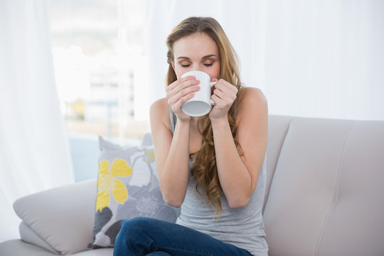 Content young woman sitting on sofa drinking from a mug
