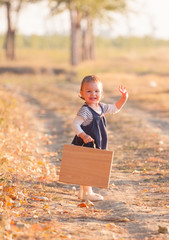 Sweet little girl playing with suitcase on the country road