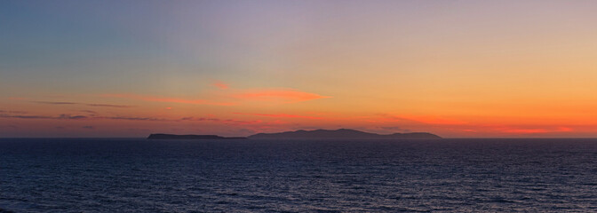 Panoramic shot of beautiful coastal sunset with some islands on