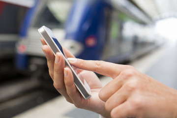 Close up of hands woman using her cell phone at a station platfo