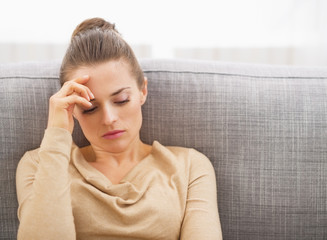 Stressed young woman sitting on sofa