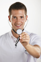 Young medical doctor man showing the stethoscope. Isolated.