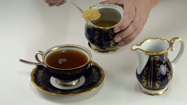 Adding brown sugar to cup of tea