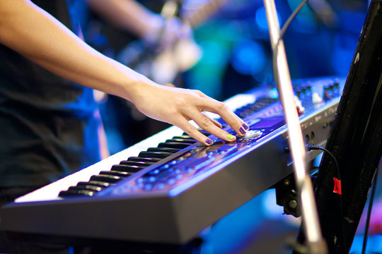 hands of musician playing keyboard in concert - Powered by Adobe