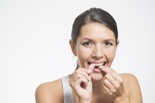 Frau benutzt Zahnseide um ihre Zähne zu pflegen