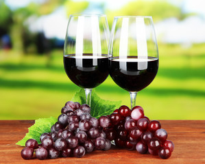 Obraz premium Ripe grapes and glasses of wine, on bright background