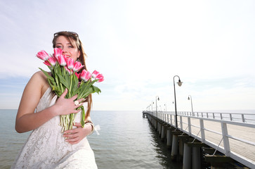 Smiling woman with bunch of flowers sea