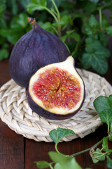 Ripe figs in leaves on wooden table close-up