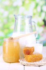 Honey and milk on wooden table on natural background