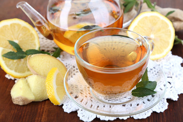 Kettle and cup of tea with ginger on napkin on wooden table