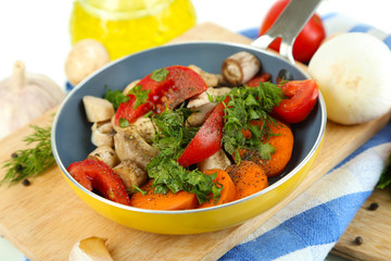 Sliced fresh vegetables in pan on wooden board isolated on