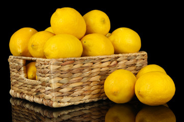 Ripe lemons in wicker basket isolated on black