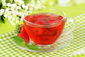 Delicious strawberry tea on table on bright background