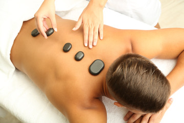 Obraz na płótnie Canvas Young man having stone massage in spa salon