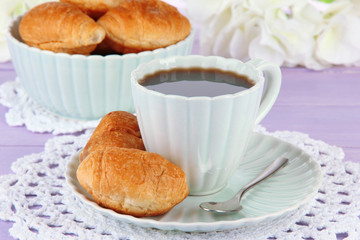 Tasty croissants and cup of coffee on table close-up