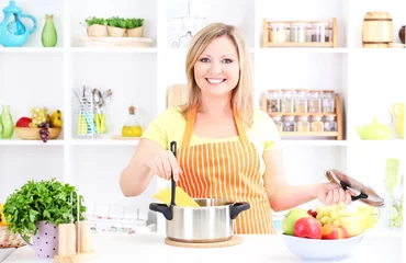 Poster Gelukkig lachende vrouw in de keuken die zich voorbereidt op een gezonde maaltijd © Africa Studio