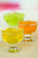Tasty jelly cubes in bowls on table on light background