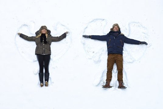 Young couple making snow angel