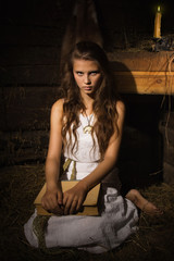 Young girl sitting with old book in a dark interior