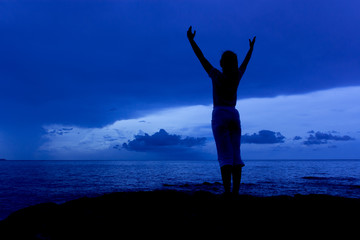 Fototapeta premium Silhouette of woman in the blue sky morning on sea beach rock